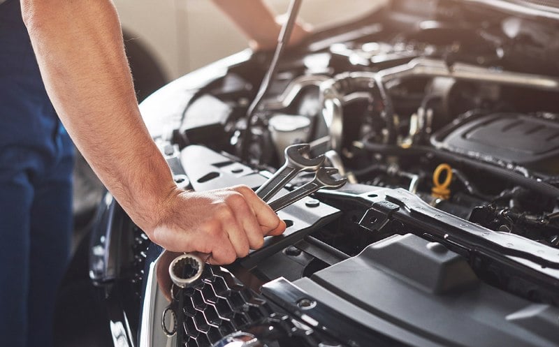 muscular-car-service-worker-repairing-vehicle